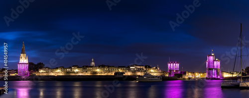 Panoramic view of the La Rochelle old harbor with its famous towers. night shot with pink lights for pink october. Pink October is breast cancer awareness month