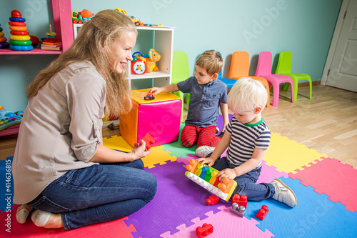 The woman educator makes up a constructor with little boys