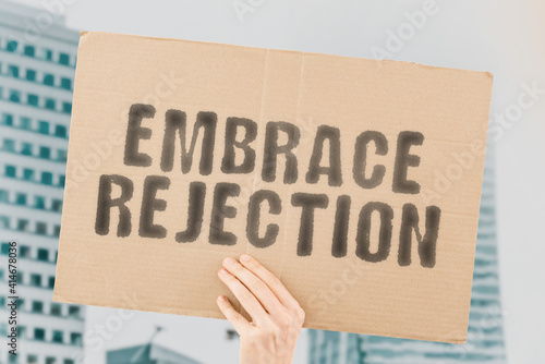 The phrase " Embrace rejection " on a banner in hand with blurred background. Knowledge. Study. Refusal. Refuse. Sickness. Mental health. Unhappy. Social. Behaviour. Desperation. Rejected