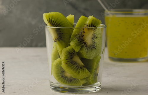 kiwi fruit salad in a glass on a gray background