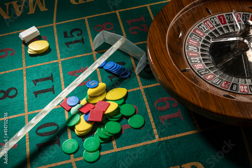 Roulette in legno isolata sopra un tavolo da gioco verde con fiches colorate