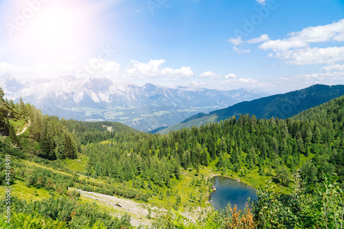 Magical idyllic landscape with lake in mountains in Alps Europe. tourist trail on green hills in Alps. Beautiful rock and admire amazing view to mountain peaks. Fantastic sunny day is in mountain lake