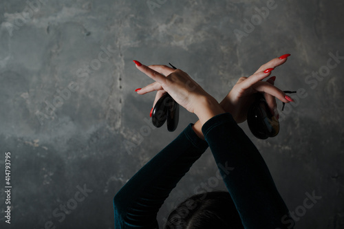 Young adult spanish woman dancing flamenco with castanets on gray vintage background