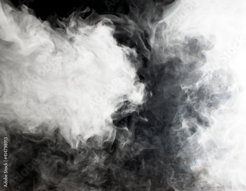 Abstract background of chaotically mixing clouds of white smoke against a background of darkness