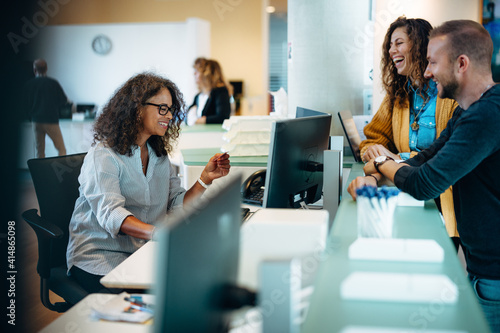 Receptionist assisting people standing at front desk