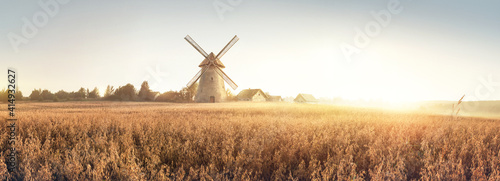 Rural landscape at dawn, terrain with oat fields and from the and a windmill and village on the hill. Raster illustration.