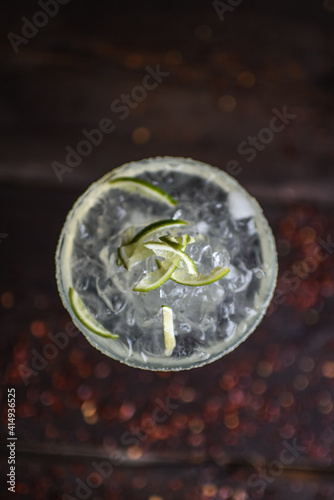 Orzeźwiający drink mojito z lodem i limonką w oszronionej szklance na tle ciemnych desek