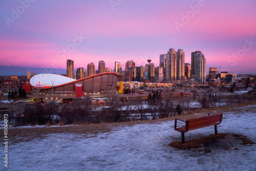 A Winter sunrise reflects in the Calgary Skyline while the opposite sky turns a neon pink and purple.