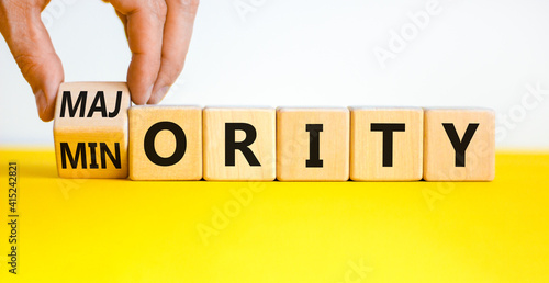 Minority or majority symbol. Businessman turns a cube and changes the word 'minority' to 'majority'. Beautiful yellow table, white background. Minority or majority and business concept. Copy space.