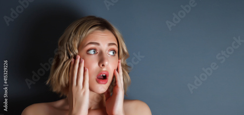 Advertising concept of surprise and fear. Close-up portrait pretty young woman scared with her hands to her face against dark isolated background. Female actress emotion scar. Copy space for site