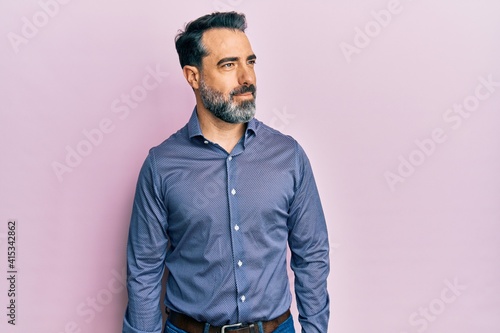 Middle age man with beard and grey hair wearing business clothes smiling looking to the side and staring away thinking.