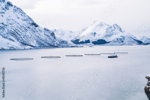 Snowy mountains on seashore with fish farm in Norway