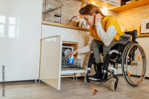 Woman in wheelchair using dishwasher