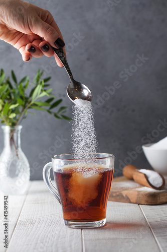 In a cup of tea, pour sugar from a teaspoon. 