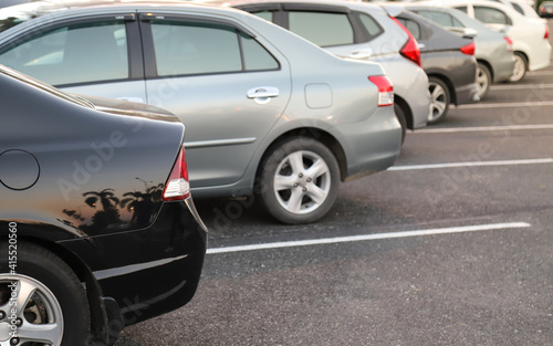 Closeup of rear or back side of black car with other cars parking in parking area.