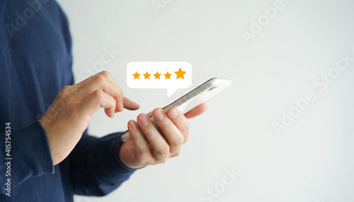 close up on customer man hand pressing on smartphone screen with gold five star rating feedback icon and press level three rank (good) for give score point to review the service business concept 