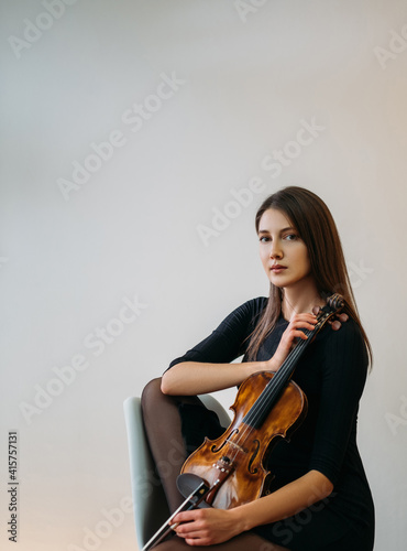 Female violinist portrait. Studio shooting. Classic music. Musician player. Artist hobby. Elegant calm woman posing with violin in hands isolated neutral background.