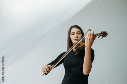 Violinist woman. Online education. Distance lesson. Lockdown reality. Inspired lady enjoying playing violin closed eyes with transparent plastic film under head isolated neutral copy space.