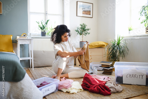 Young woman sorting wardrobe indoors at home, charity donation concept.