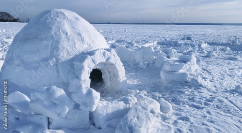 igloo and snow shelter in high snowdrift with mountains peaks on background