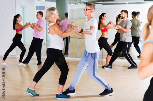 Cheerful positive people of different ages having dancing class in classroom