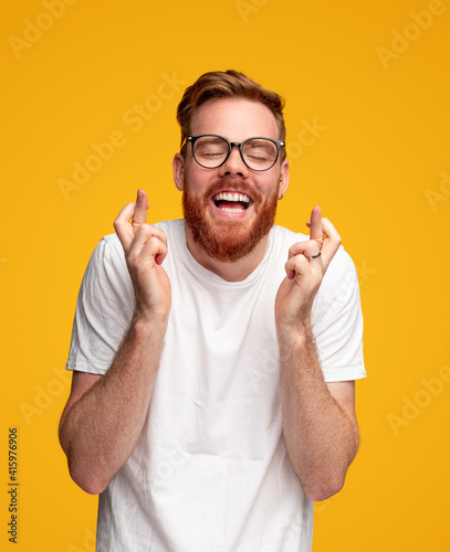 Cheerful man crossing fingers and making wish