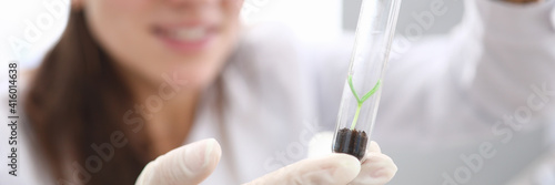 Female hands in white gloves hold test tube with earth and scion inside. Breeding and research of new plant species. Growing seed in laboratory. Environmental protection concept.