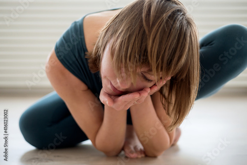 Woman is engaged in bodily practice and holds her head carefully