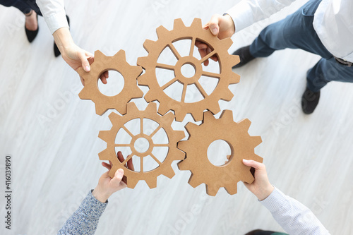 Group of business people stacking wooden gears top view