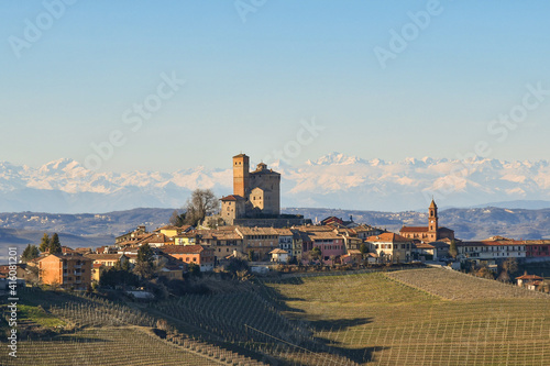 Landscape of the Langhe hills, UNESCO World Heritage Site since 2014, with the medieval Castle of Serralunga d'Alba and the Alps mountain range in the background in winter, Cuneo, Piedmont, Italy