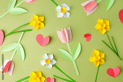 Pink origami tulips and yellow origami narcissus on green pastel background. Top view. Paper cut art. Springtime seasonal background. hallo spring concept, banner, flyer, invitation, cute card