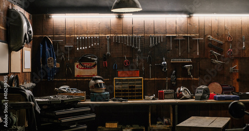 Workshop scene. Old tools hanging on wall in workshop, Tool shelf against a table and wall, vintage garage style