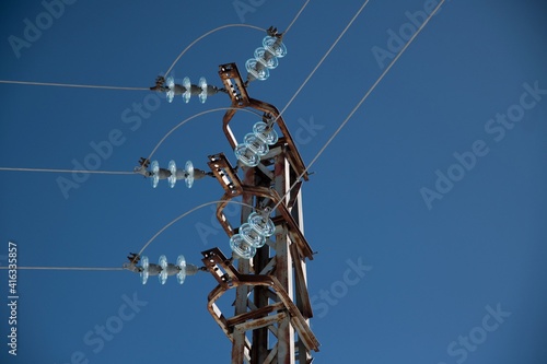 metal electricity pole with glass insulator and clear blue sky close up