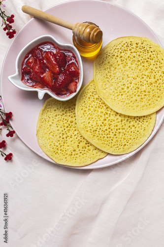 Homemade traditional moroccan baghrir with honey, strawberries and mint from above