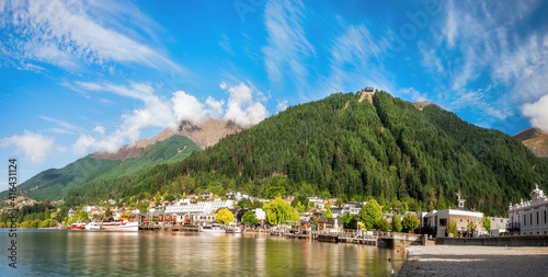 Panoramic view of the alpine city of Queenstown in New Zealand, from the marina bay of Lake Wakatipu with the Queenstown Skyline mountain in the background.