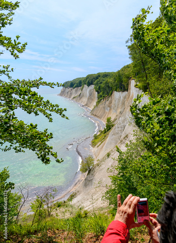 woman takes a picture of the chalk coast of Ruegen from above the cliffs, Germany