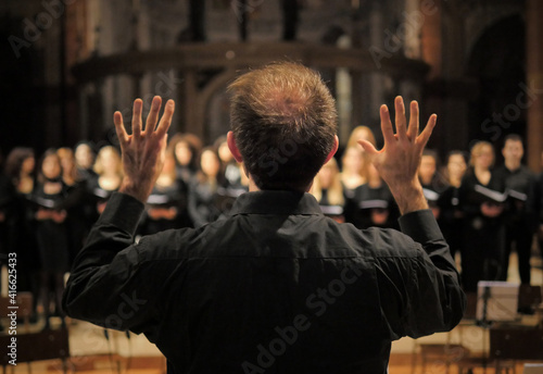 Musician leads a choir during a concert in a cathedral. Musical rehearsals before the concert during the Christmas period. Life of musicians and classic holy music.