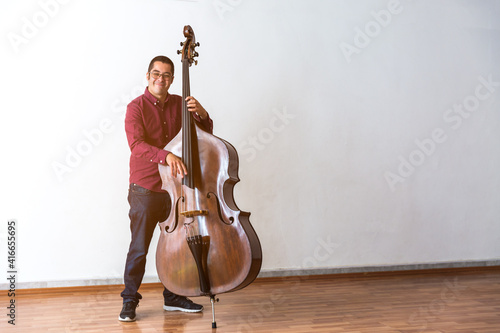 Professional double bass player. Photo shooting in studio. White background