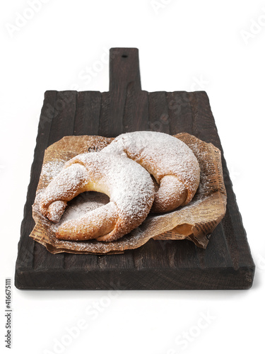 sugar covered croissants (rogalik) on a dark wooden cutting board side view on a white background isolated closeup. Selective focus