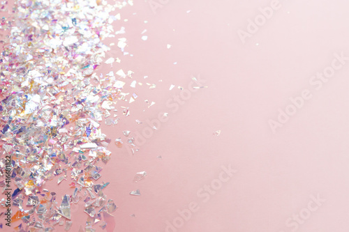 neon pearl foil confetti on light pink background. Festive, party or holiday glowing backdrop. Flat lay, top view.