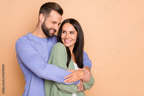 Photo of optimistic couple hug look with empty space wear cardigan sweater isolated on beige color background