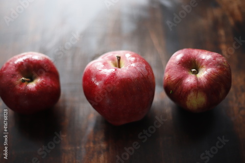 Jabłka czerwono mokre na brązowym stole