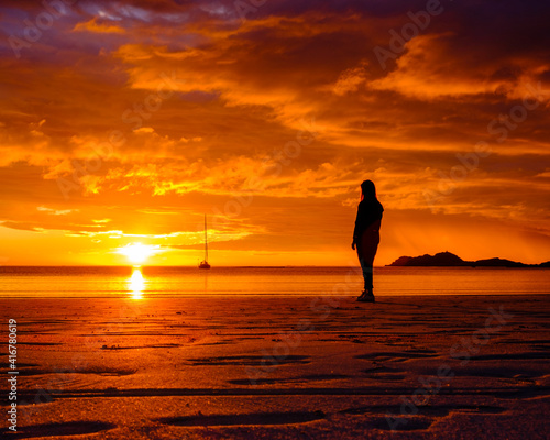 Woman in silhouette. Sunset at Ramberg beach in Lofoten islands, Norway