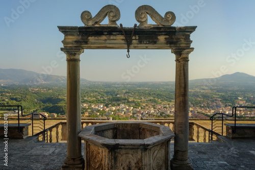 The ancient water well in front of Palazzo Colonna Barberini with panorama with hills near Rome on the background, Palestrina, Italy