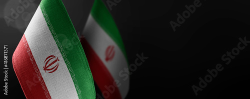 Small national flags of the Iran on a dark background