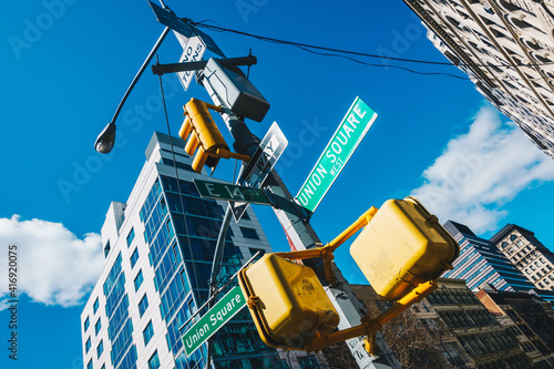 Street sign of Union Square and East 14 St with skylines in background.- New York, USA