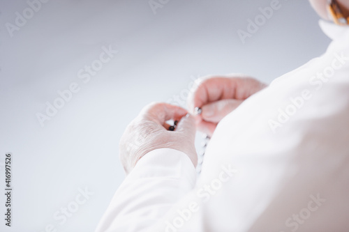 Nun dressed in white and sitting on the chair holding the rosary in hand and praying. Selective focus. Hope concept
