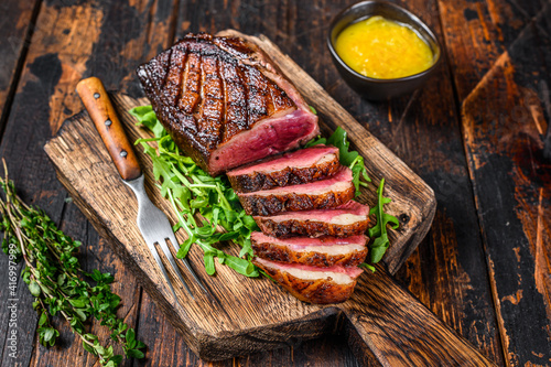 Sliced grilled duck meat breast fillet steak. Dark wooden background. Top view