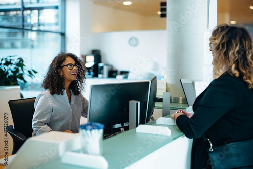 Friendly administrator assisting woman at reception desk