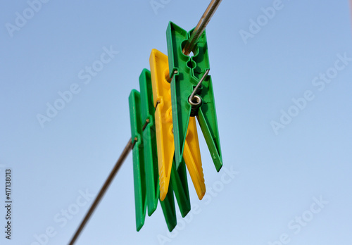 Mollette da bucato di colore verde e giallo appese ad un filo per stendere i panni ad asciugare.